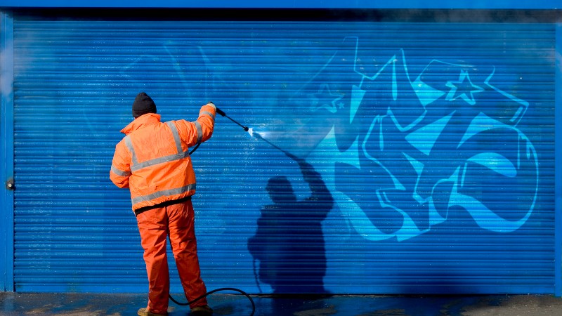 Man in high vis clearing graffitti